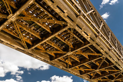 Steel lattice construction of a railway bridge on a background of blue sky with white clouds.