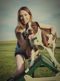 Portrait of woman with dog on field