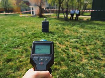 Cropped hand of man counting radiation over grassy field