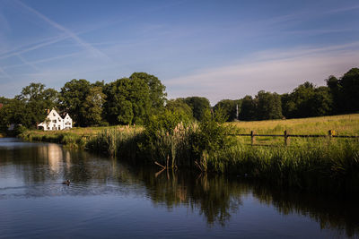 River by grassy field against sky