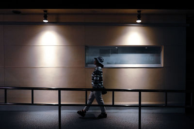 Woman walking in illuminated walkway at night