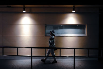 Low section of woman against illuminated wall at night