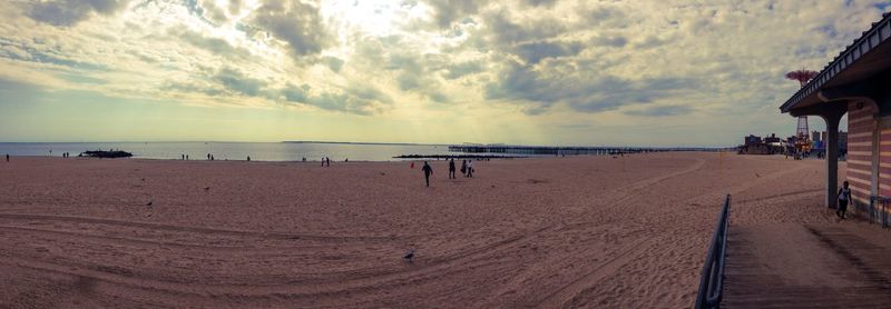 View of calm beach against cloudy sky