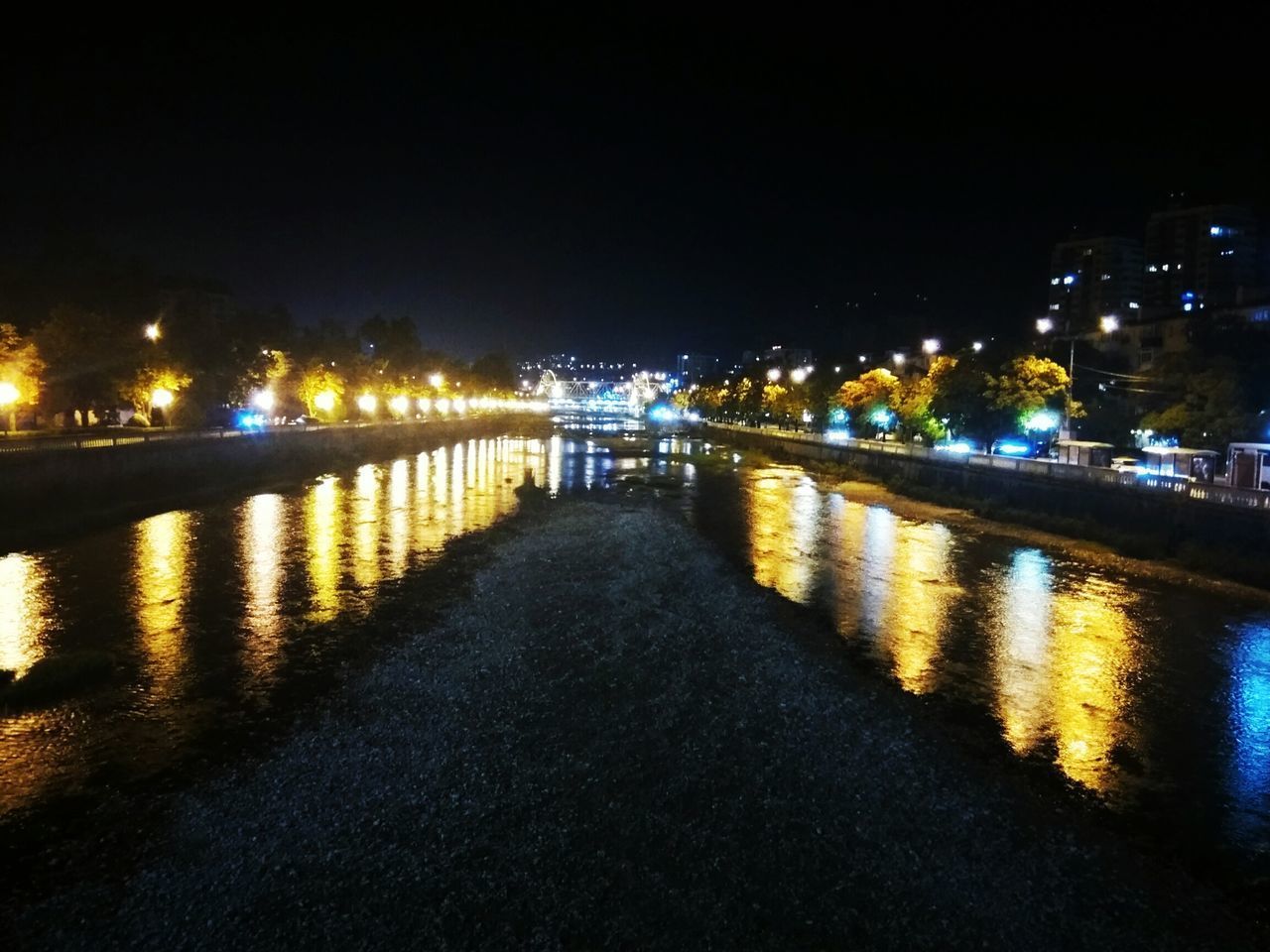 ILLUMINATED BRIDGE OVER RIVER IN CITY AT NIGHT