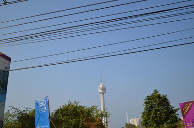 Low angle view of trees and buildings against clear blue sky