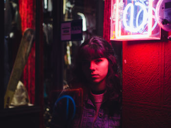 Portrait of young woman by illuminated lighting equipment at night