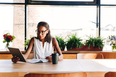 Young woman using phone while sitting on table