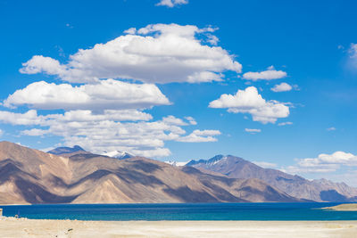 Scenic view of sea and mountains against blue sky