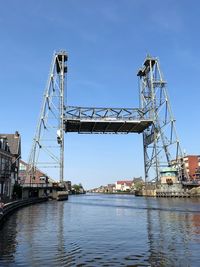 Low angle view of bridge over river against clear blue sky