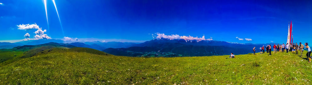 Group of people on mountain against blue sky