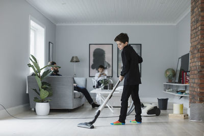 Boy vacuuming floor in living room at home