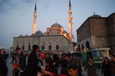 Crowd outside yeni cami mosque against sky at dusk