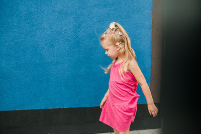 Portrait of young woman standing against blue wall