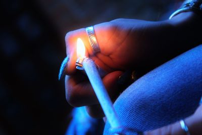 Midsection of woman lighting joint at night