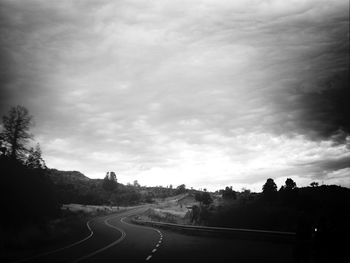 View of country road against cloudy sky