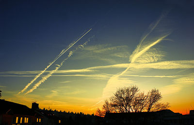 Low angle view of silhouette trees and buildings against sky during sunset