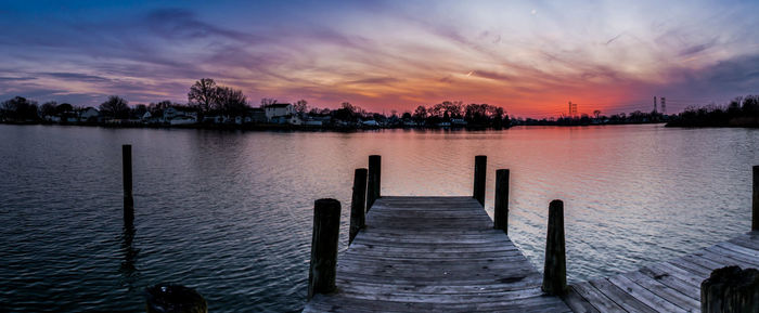 Pier over lake against sky during sunset