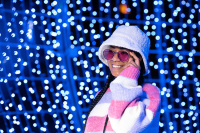 Joyful woman of color with a white beanie braided hairstyle and pink glasses enjoying the christmas