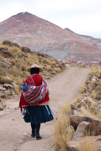 Rear view of woman walking at desert against sky