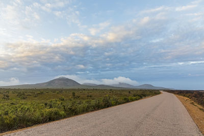 Road leading towards mountains against sky