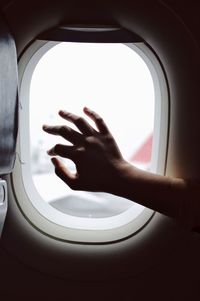 Cropped hand touching window in airplane