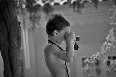 Side view of shirtless boy looking through binoculars