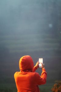 Rear view of man photographing with mobile phone