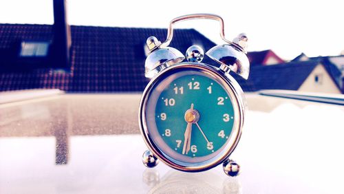 Close-up of alarm clock on table against houses