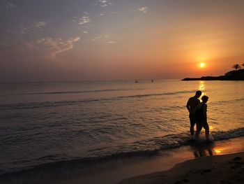 People on beach against sky during sunset