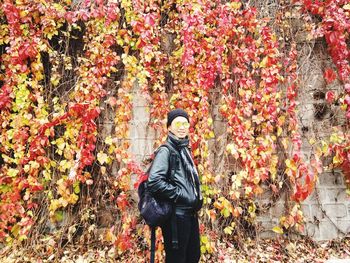 Full length of young man standing by plants during autumn