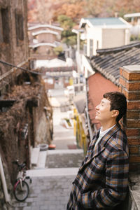 Side view of smiling man standing against building in city