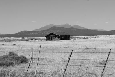 House on field by mountain against sky