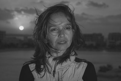 Close-up of thoughtful woman looking away while standing against sky at night