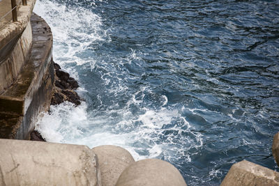 High angle view of sea waves splashing on rock formation