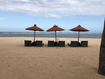 Deck chairs on beach against sky