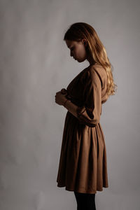 Side view of woman standing against white background