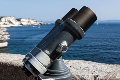 Close-up of coin-operated binoculars by sea against clear sky