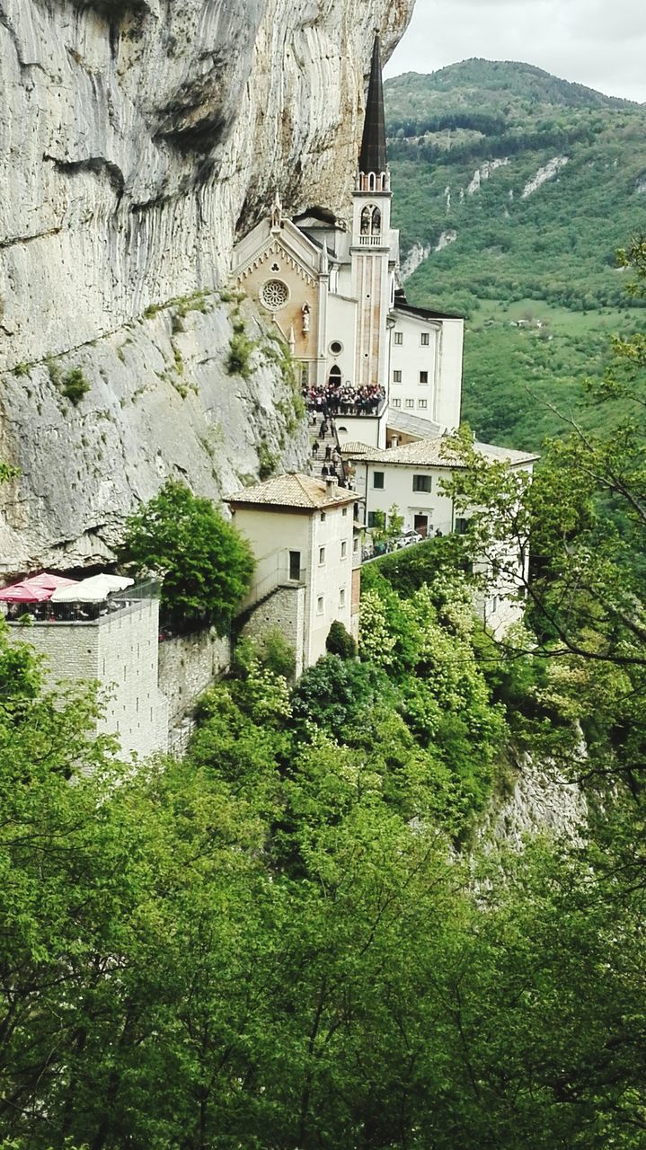 built structure, architecture, building exterior, mountain, plant, building, day, nature, tree, water, no people, green color, beauty in nature, rock, growth, outdoors, place of worship, solid, mountain range, formation