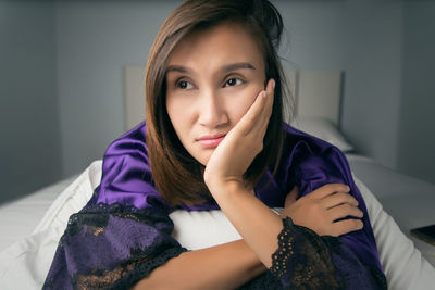 Close-up of thoughtful woman looking away while lying on bed at home