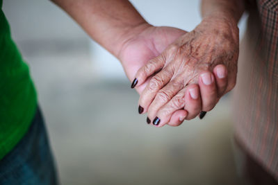 Close-up of man holding senior woman hands