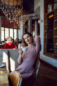 Woman in a pink dress sitting in a restaurant with a cup of tea