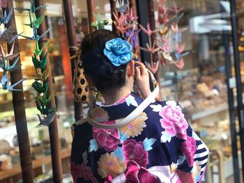 Portrait of woman standing by paper cranes for sale