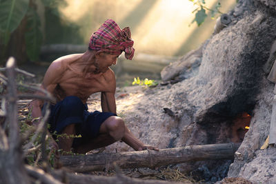 Senior man burning bamboo in forest