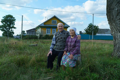 Rear view of man and woman standing on grass against sky