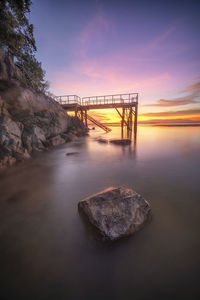 Bridge over sea against sky during sunset