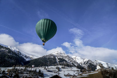 Scenic view of hot air ballon in front of snowcapped mountains against sky
