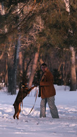 Low section of man standing on snow covered field