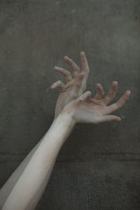 Cropped hands of woman gesturing against wall