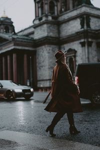 Full length of tourist walking on wet road in city during rainy season