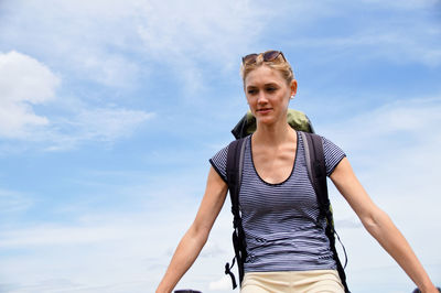 Low angle view of young woman standing against sky